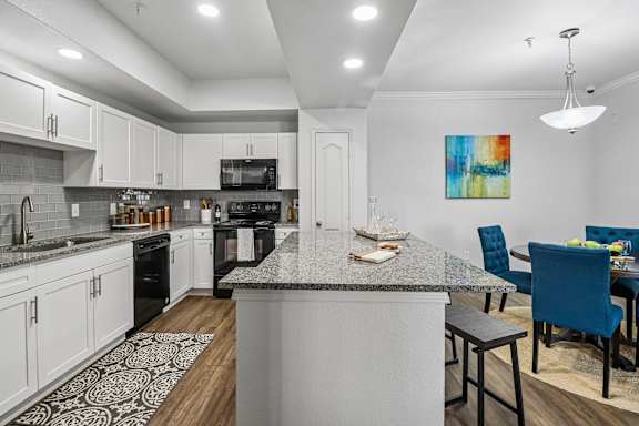A kitchen with a large island and a dining area with blue chairs.