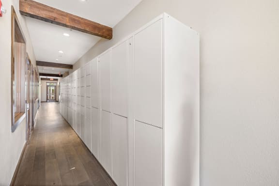 a long row of white cabinets in a hallway with wood floors at Lakeline East Apartments, Cedar Park