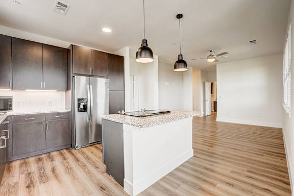 A kitchen with a white island and dark brown cabinets.