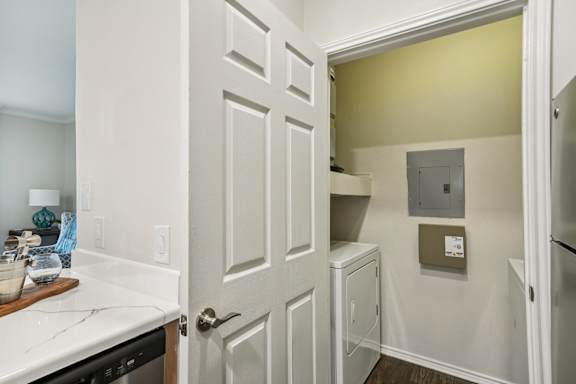 A white door is open to a small room with a white cabinet and a brown box on the wall.