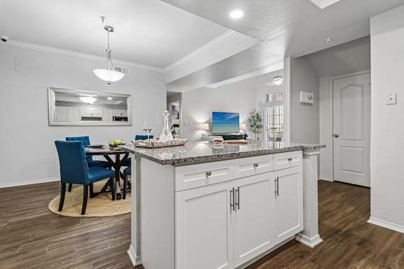 A kitchen with a blue chair and white cabinets.