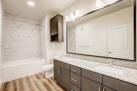 A bathroom with a marble patterned wall and a white toilet.
