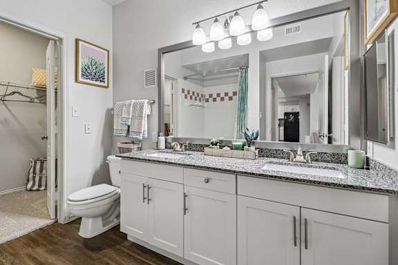 A bathroom with a toilet, sink, and mirror.
