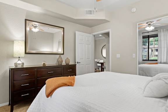 A bedroom with a large bed, a dresser, and a mirror.