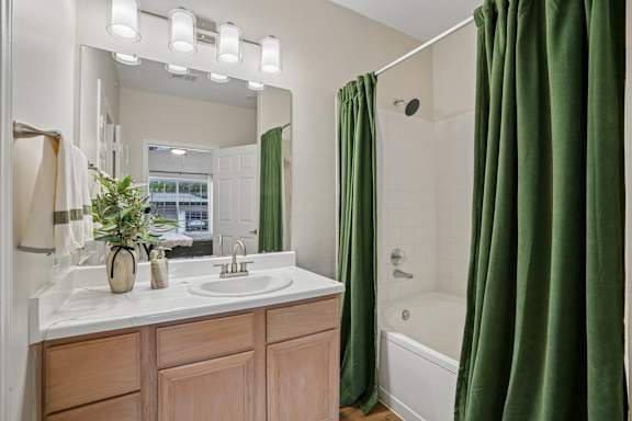 A bathroom with a white sink and green curtains.