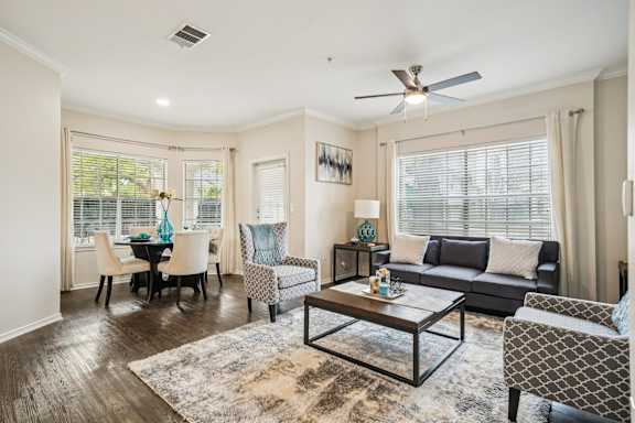 A living room with a black couch, a coffee table, and a dining table with chairs.
