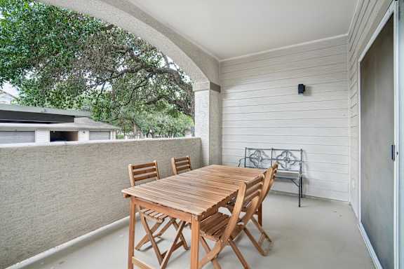 A wooden table and chairs are set up on a patio.