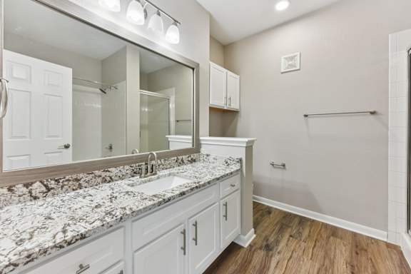 A bathroom with a marble countertop and white cabinets. at Sonterra Apartment Homes, Austin, TX, 78726
