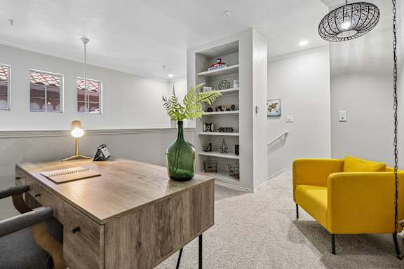 A room with a desk, chair, and a yellow couch.
