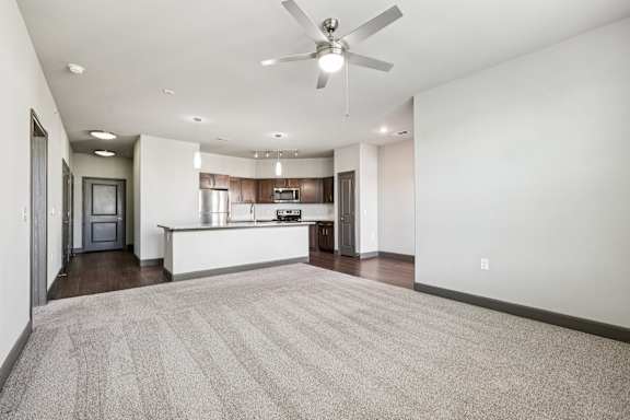A spacious living room with a carpeted floor and a ceiling fan.at North Creek, Hutto, TX, 78634