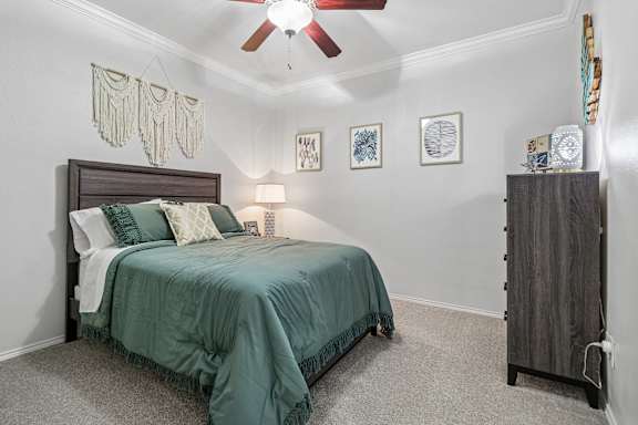 A bedroom with a bed, a ceiling fan, and a cabinet.