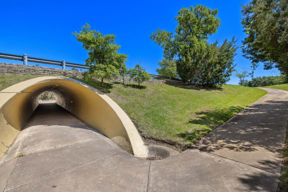 a tunnel on the side of a hill with grass and trees at Lakeline East Apartments, Cedar Park, TX