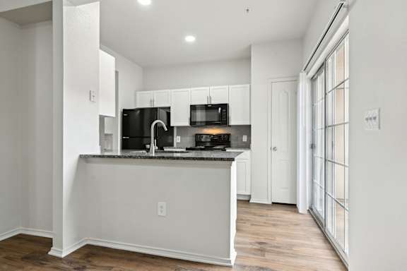 A kitchen with white cabinets and a dark countertop.