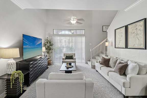 A living room with a white couch, a black coffee table, and a large painting on the wall.