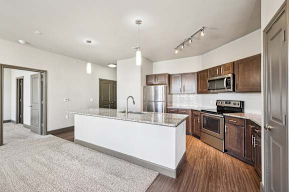 A modern kitchen with a white island and wooden cabinets.at North Creek, Hutto