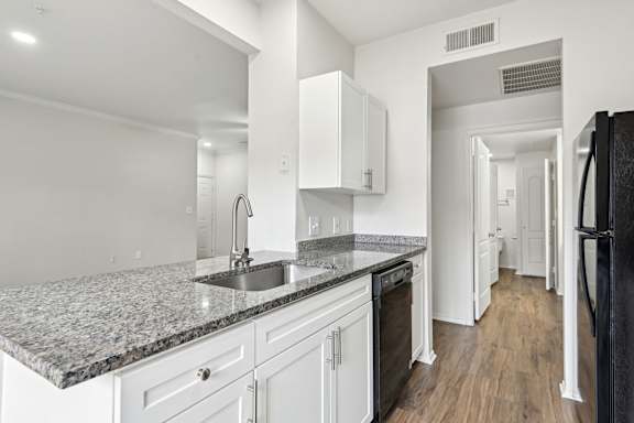 A kitchen with granite countertops and white cabinets.