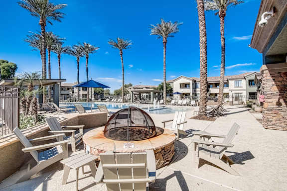 a fire pit with chairs around it near a pool with palm trees  at Adiamo Palm Valley, Goodyear, AZ, 85395