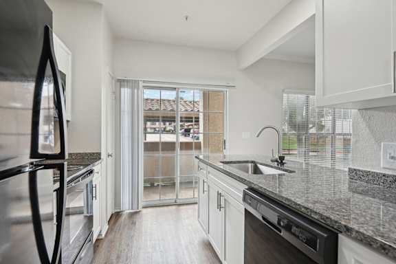 A kitchen with a black fridge and a black dishwasher.