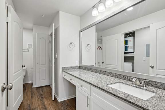 A bathroom with a sink, mirror, and cabinets.
