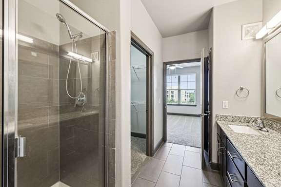 A modern bathroom with a walk-in shower and a large mirror.at North Creek, Hutto, TX