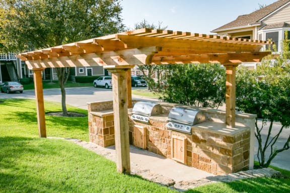 a wooden pergola with two brick barbecue pits in a yard at The Legends at Eagle Mountain Lake, Fort Worth, TX