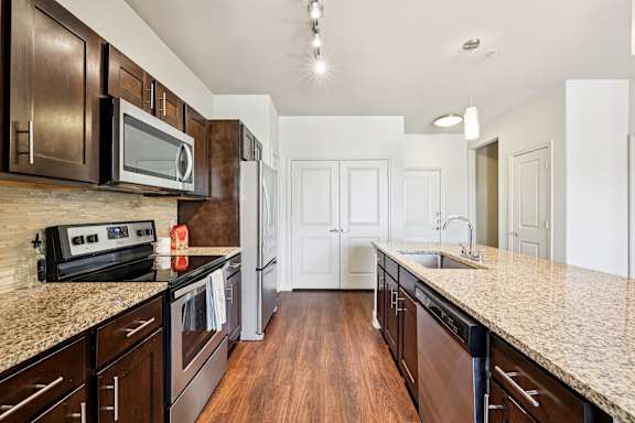 A kitchen with dark brown cabinets and granite countertops. at North Creek, Texas