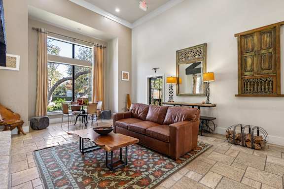 A living room with a brown leather couch and a patterned rug.