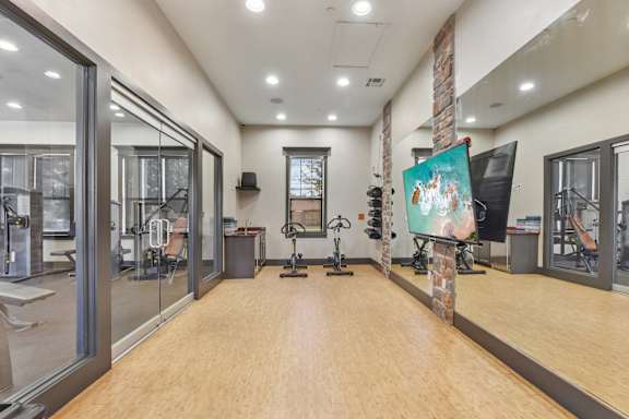 A gym with wooden floors and various exercise equipment.