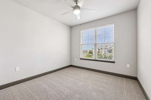 A room with a carpeted floor, a ceiling fan, and a window with blinds.at North Creek, Hutto, 78634