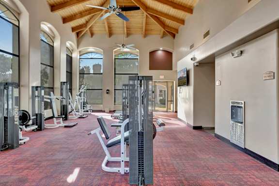 A gym with a variety of equipment including treadmills, weights, and a bench press. at San Montego Apartments, Mesa, AZ