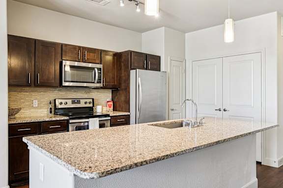 A kitchen with a granite countertop and white cabinets.at North Creek, Hutto, TX
