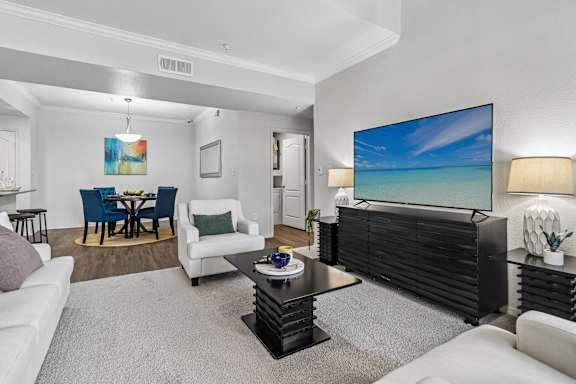 A living room with a large screen TV on the wall.