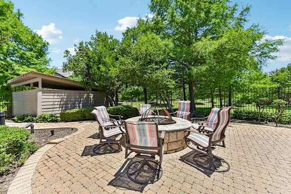 A patio with a table and chairs surrounded by trees.