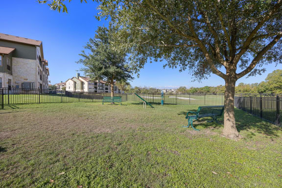 a park with a tree and a bench in front of a fence at The Fairways at Star Ranch, Hutto, TX