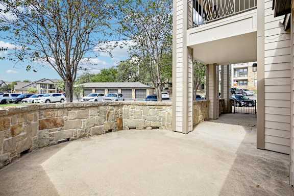 A stone wall separates a parking lot from a building.