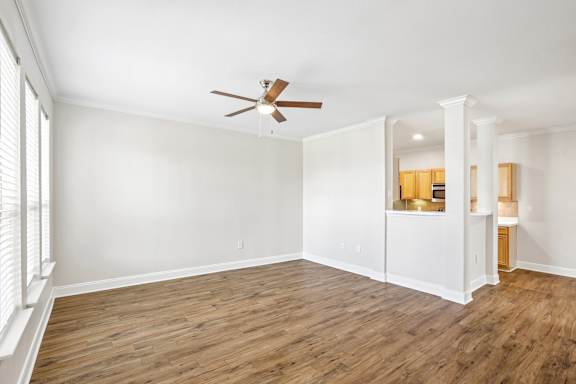 A room with a ceiling fan and wooden flooring.