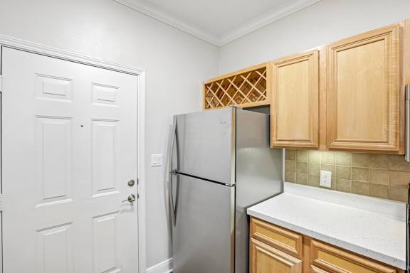 A kitchen with a refrigerator and wooden cabinets.