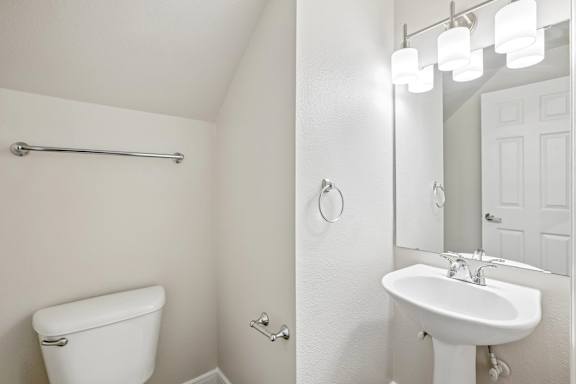 A white bathroom with a toilet, sink, and mirror.