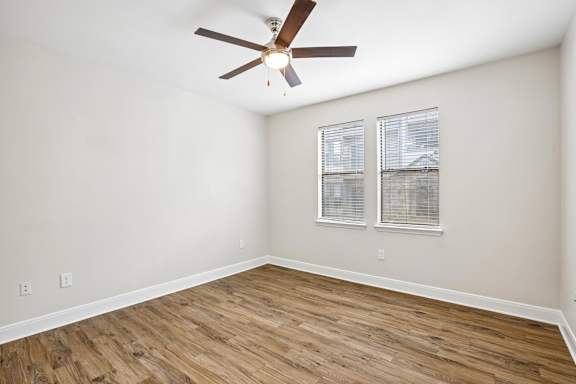 A room with a ceiling fan and wooden flooring.