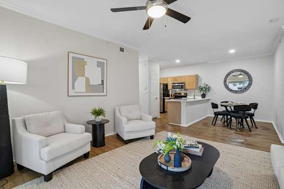 A living room with a white sofa, a black coffee table, and a ceiling fan.