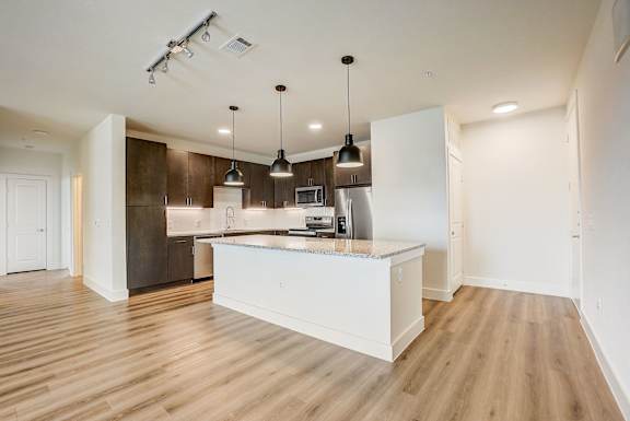 A kitchen with a white island and pendant lights.