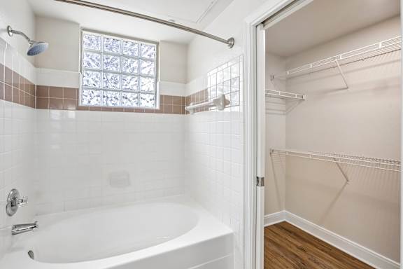A white bathtub with a shower head and a window above it.