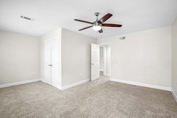 A room with a ceiling fan and carpeted floor.