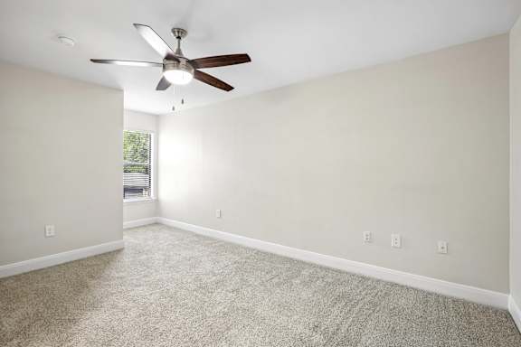 A room with a ceiling fan and carpeted floor.
