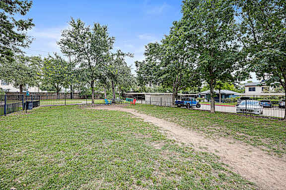 a grassy area with trees and a fence at Artisan Apartments & Shops, Austin