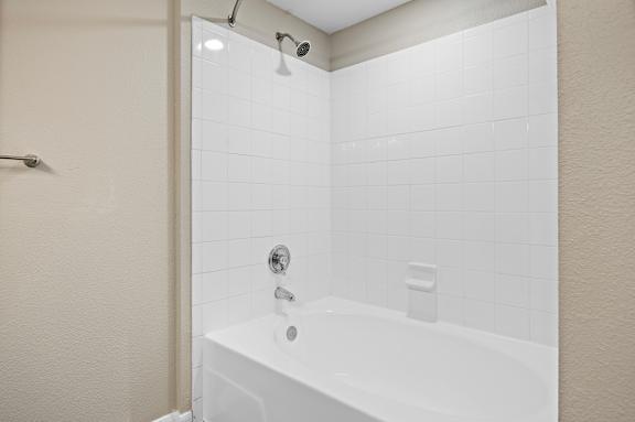 A white bathtub with a shower head above it.