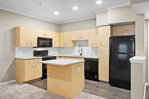 an empty kitchen with black appliances and wooden cabinets at Artisan Apartments &amp; Shops, Austin, Texas