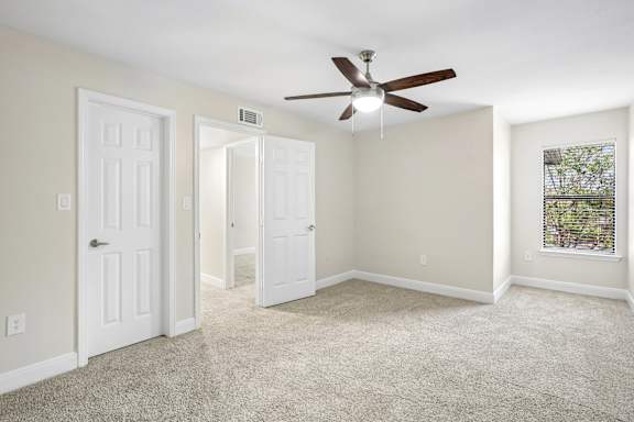 A room with a ceiling fan and carpeted floor.