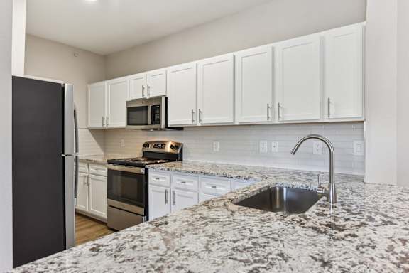 A kitchen with granite countertops and white cabinets. at Sonterra Apartment Homes, Austin, TX