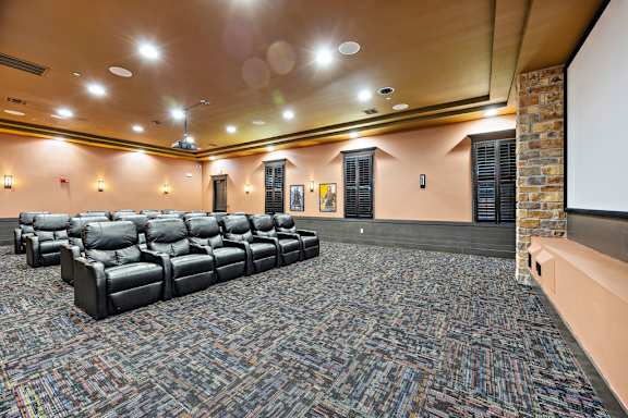 A room with a carpeted floor and a row of black leather chairs.